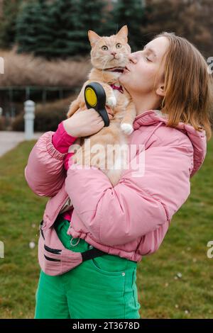 Jeune femme portant et embrassant le chat dans le parc Banque D'Images