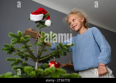 Fille souriante décorant l'arbre de Noël à la maison Banque D'Images