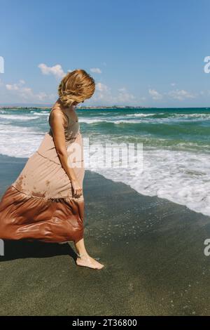 Femme debout sur le sable humide près du rivage à la plage Banque D'Images