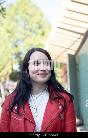 Jeune femme souriante portant une veste en cuir rouge Banque D'Images