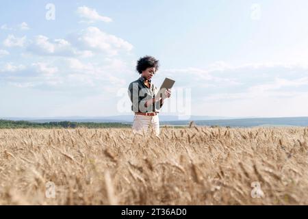 Afro agronome tenant le comprimé PC au milieu des cultures d'orge au champ Banque D'Images