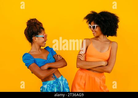 Femmes debout avec les bras croisés sur fond jaune Banque D'Images