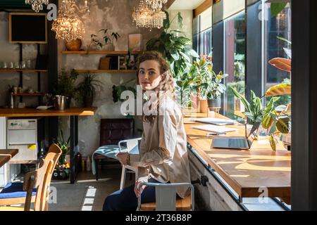 Jeune femme d'affaires assise près de la table au café Banque D'Images