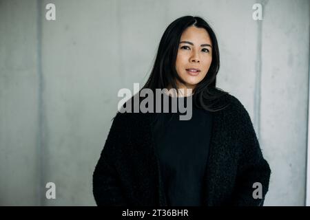 Femme d'affaires confiante devant le mur au lieu de travail Banque D'Images
