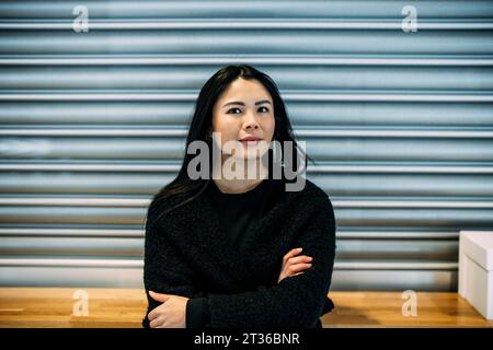 Confiante belle femme d'affaires avec les bras croisés au bureau Banque D'Images