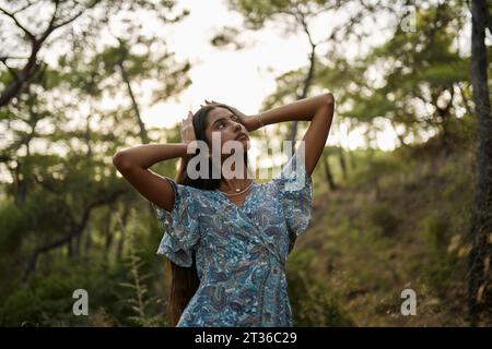 Adolescente avec la tête dans les mains debout à la forêt Banque D'Images