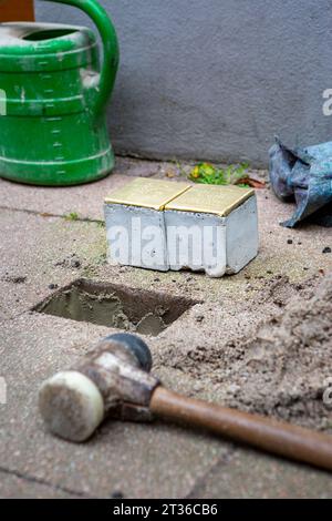 Wiesbaden, Allemagne - 17 octobre 2023 : un maçon pose Stolpersteine sur un trottoir dans le centre-ville de Wiesbaden, Allemagne. Un Stolperstein (littéralement « pierre d'achoppement ») est un cube de béton muni d'une plaque de laiton portant le nom et les dates de vie des victimes de l'extermination nazie. Banque D'Images