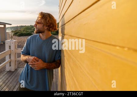 Jeune homme aux cheveux blonds appuyé sur la cabane de plage Banque D'Images