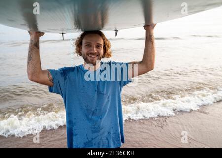 Homme heureux portant paddleboard près de la mer à la plage Banque D'Images