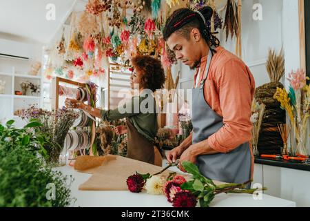 Jeunes fleuristes faisant bouquet de fleurs au bureau dans la boutique Banque D'Images