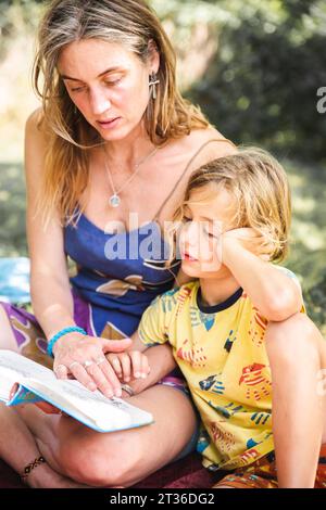 Mère lisant le livre à son fils dans la forêt Banque D'Images