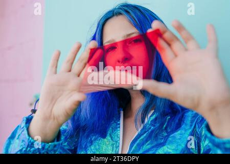 Femme hipster regardant à travers le verre rouge Banque D'Images