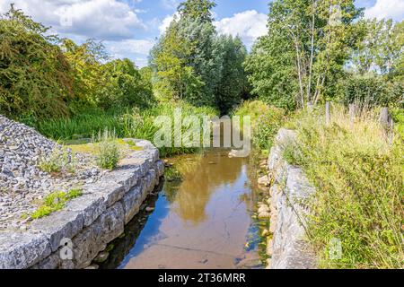 Canal sur la rivière Geul accolé au vieux moulin à eau Eper ou Wingbergermolen, arbres et végétation sauvage contre ciel bleu en arrière-plan, journée ensoleillée à Terpoor Banque D'Images