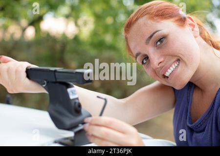 femme met des choses dans la galerie de toit de la voiture Banque D'Images