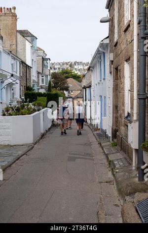 Vacanciers marchant sur une route étroite à St Ives, Cornouailles, Royaume-Uni Banque D'Images