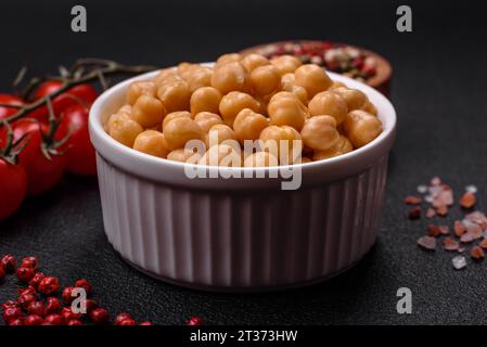 Délicieux pois chiches en conserve dans une assiette en céramique sur un fond de béton foncé. Ingrédient pour plats végétariens Banque D'Images