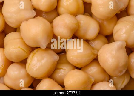 Délicieux pois chiches en conserve dans une assiette en céramique sur un fond de béton foncé. Ingrédient pour plats végétariens Banque D'Images