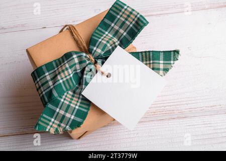 Maquette d'étiquette cadeau carrée de Noël avec boîte cadeau emballée artisanalement sur un fond blanc Banque D'Images