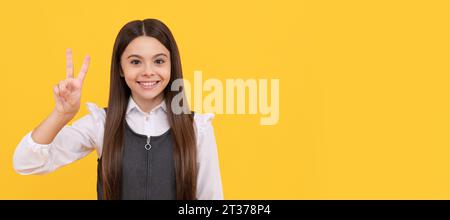 V est pour la victoire. Enfant fille heureuse donner signe de victoire. L'éducation scolaire. Visage d'enfant, affiche horizontale, portrait isolé de fille adolescente, bannière avec co Banque D'Images