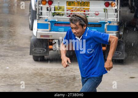 SAMUT PRAKAN, THAÏLANDE, SEP 25 2023, chauffeur de Tuk Tuk courant dans la rue sous la pluie Banque D'Images