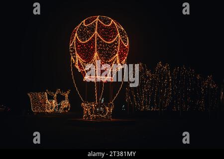 Figure étincelante dans l'installation de rue dark.Christmas de guirlandes brillantes. Ballon lumineux, renne avec traîneau Banque D'Images