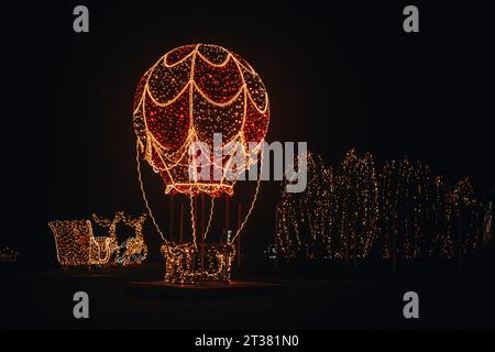 Figure étincelante dans l'installation de rue dark.Christmas de guirlandes brillantes. Ballon lumineux, renne avec traîneau fait de guirlandes. Noël Banque D'Images