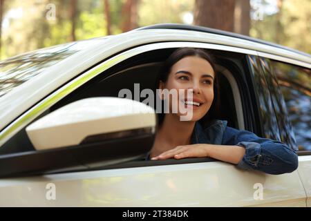 Heureuse jeune femme regardant par la fenêtre de la voiture, vue de l'extérieur. Bon voyage Banque D'Images