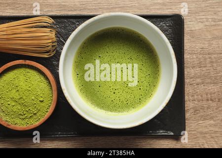 Tasse de thé matcha frais, fouet en bambou et poudre verte sur table en bois, vue de dessus Banque D'Images