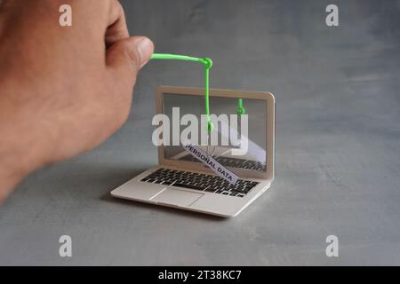 Image rapprochée d'un ordinateur portable et d'un hameçon avec DES DONNÉES PERSONNELLES textuelles. Concept d'attaque par hameçonnage Banque D'Images