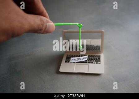 Image rapprochée d'un ordinateur portable et d'un hameçon avec DES INFORMATIONS PERSONNELLES textuelles. Concept d'attaque par hameçonnage Banque D'Images