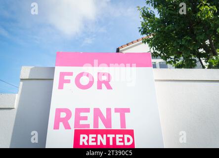 Marché de location chaud - "Maison à louer" et signe immobilier "loué" devant une maison sur le mur de clôture blanc. Auckland. Banque D'Images