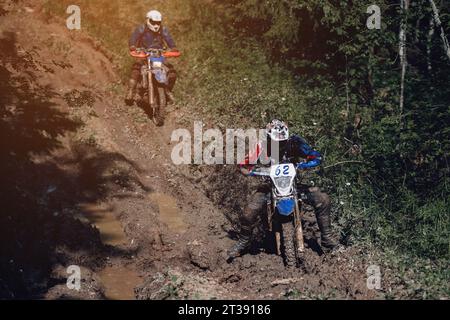 moto coureur sur enduro sports moto promenades sur une route boueuse avec des flaques dans la forêt dans la course hors route sur une journée ensoleillée Banque D'Images