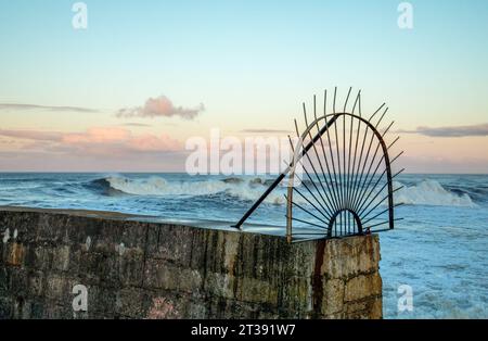 Grosses vagues au crépuscule pendant la queue d'une tempête au-dessus d'un mur du port Banque D'Images