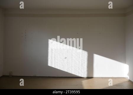 Lumière de la fenêtre sur le mur d'un salon vide non rénové dans un ancien appartement de logement public, architecture, rénovation et concep intérieure Banque D'Images