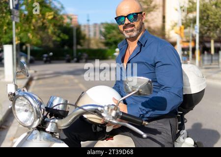 Homme d'affaires sur une moto sur une journée ensoleillée dans la ville Banque D'Images