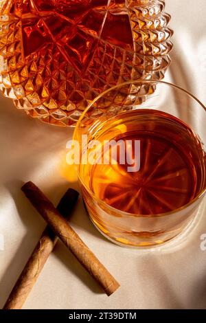 Vue de dessus du verre de whisky placé sur la table près de carafe et bâtons de cannelle Banque D'Images