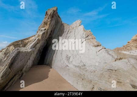 Vue de dessous des formations rocheuses à Arnia Beach en Cantabrie, Espagne, contre un ciel bleu clair Banque D'Images