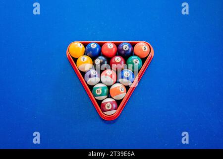 Vue de dessus de la pyramide colorée de boules de billard dans le triangle de billard sur la table de billard bleue Banque D'Images