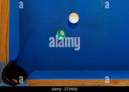 Vue de dessus des boules de billard vertes et blanches sur la table de billard bleue près de la poche Banque D'Images