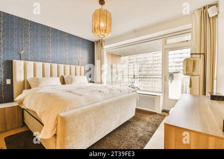 Lit confortable avec oreillers et couette placé par une grande fenêtre lumineuse dans la chambre à coucher à l'appartement moderne Banque D'Images