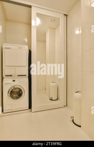 Lave-linge et sèche-linge par cabine de douche avec portes coulissantes dans une salle de bains blanche moderne à la maison Banque D'Images