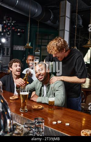 homme redhead touchant les épaules du marié afro-américain pendant la fête de célibataire, amitié masculine Banque D'Images