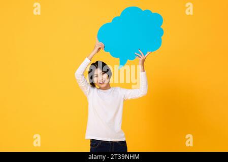 Jeune femme asiatique souriant et tenant la bulle de parole en fond de studio isolé de couleur jaune Banque D'Images