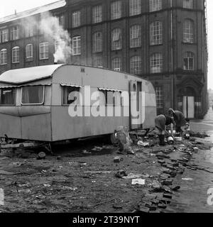 La famille des voyageurs et leur caravane garés sur des terres vagues à côté d'une usine pendant le déminage et la démolition de St ann's, Nottingham. 1969-1972 Banque D'Images
