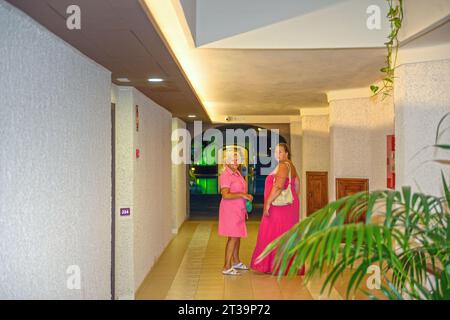 Deux femmes, mère et fille en robes rouge vif sont debout dans l'intérieur du hall. Banque D'Images