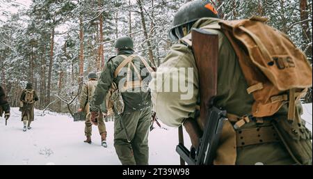 Héros de la guerre. Des réacteurs habillés en soldat d'infanterie américain marchant sur Forest Road lors de Cold Winter Day. Groupe de soldats américains marchant Banque D'Images