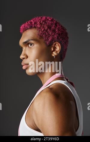 portrait de jeune homme beau avec les cheveux roses et boucles d'oreilles posant dans le profil, la mode et le style Banque D'Images