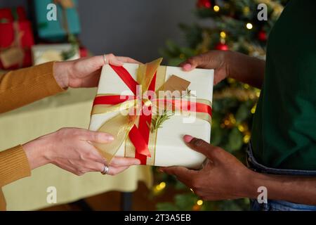 Amis échangeant des cadeaux de Noël à la fête à la maison Banque D'Images