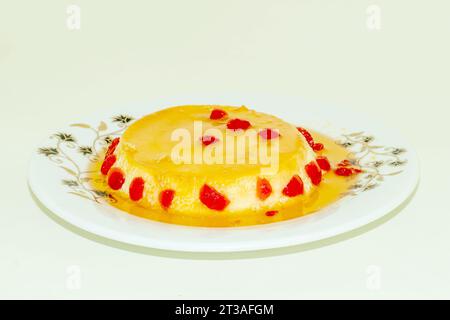 Les cerises rouges sont des fruits sucrés, polyvalents et estivaux. Un pudding merveilleusement aromatisé fait avec du lait d'oeuf et du sucre et servi nappé de cerise rouge f Banque D'Images