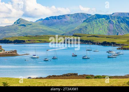 La belle île de Canna, Hébrides intérieures en été avec des yachts et un catamaran dans la baie et une CÔTE s'accélérant vers le port avec l'île de R. Banque D'Images